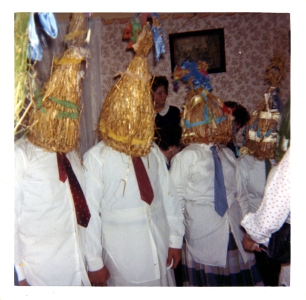 Four 'strawboys' at a wedding wearing headwear made of rushes and white shirts