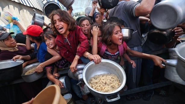 Starving Palestinian children shove to receive a hot meal from a charity kitchen in the Nuseirat refugee camp