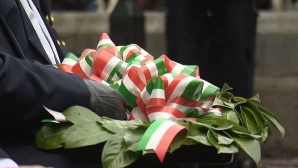 A man holding a wreath with the Tricolour on it