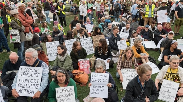 People sit on the ground holding placards