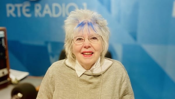 writer Margaret Hickey, in RTÉ Radio studio, behind mic and smiling into camera, 2024