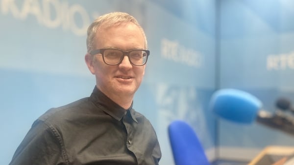 architect Emmett Scanlon in RTÉ Radio studio, behind mic, smiling to camera, 2024