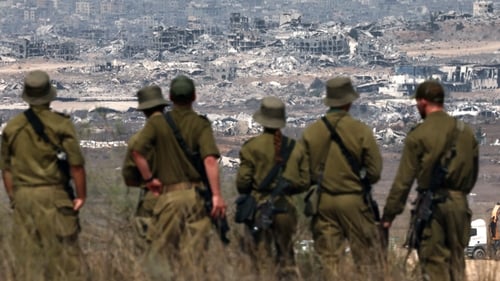 Israeli army soldiers look at destroyed buildings in the Gaza Strip as they stand on the border with the Palestinian territory, on August 13, 2025. Photo: Getty Images