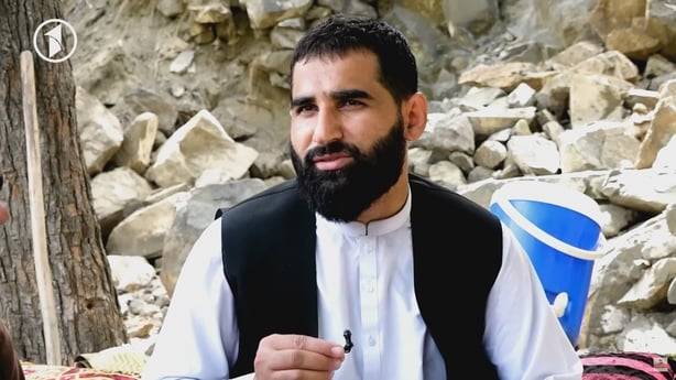 Sangar Hashimi sits in front of rubble.