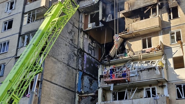 Rescuers using a crane to clear rubble in destroyed apartments of a residential high-rise building.