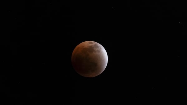 The moon is seen as it is nearly completely shrouded by the shadow of the earth as it heads into a total Lunar eclipse known as the "blood moon" from the Samburu National Reserveon