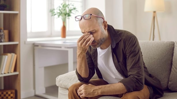 A man pinching his nose in pain with a headache
