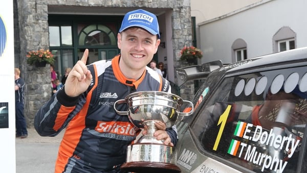 New champion Eddie Doherty with the Cecil Vard Memorial Trophy holding one finger up in the number one pose with his rally car in the background