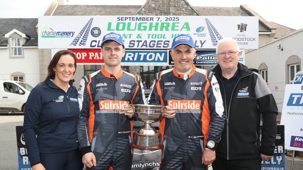 National Rally Champions Eddie Doherty and Tom Murphy flanked by championship officials Laura McMenamin and Declan Tumulty holding trophy in front of advertising signage at the event in Clare 