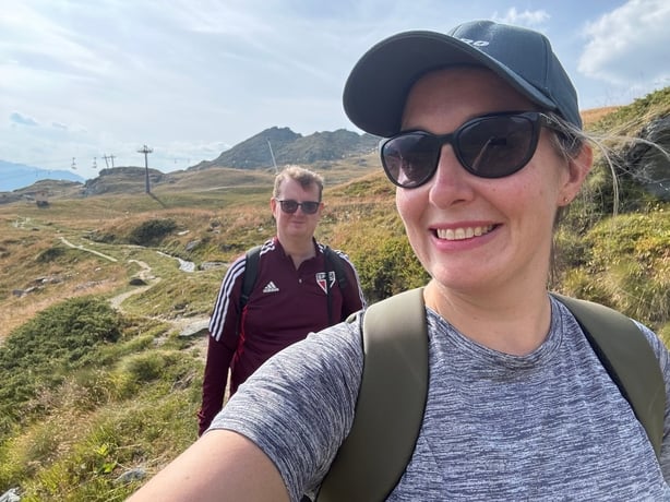 A woman talking a selfie of her and her partner while hiking
