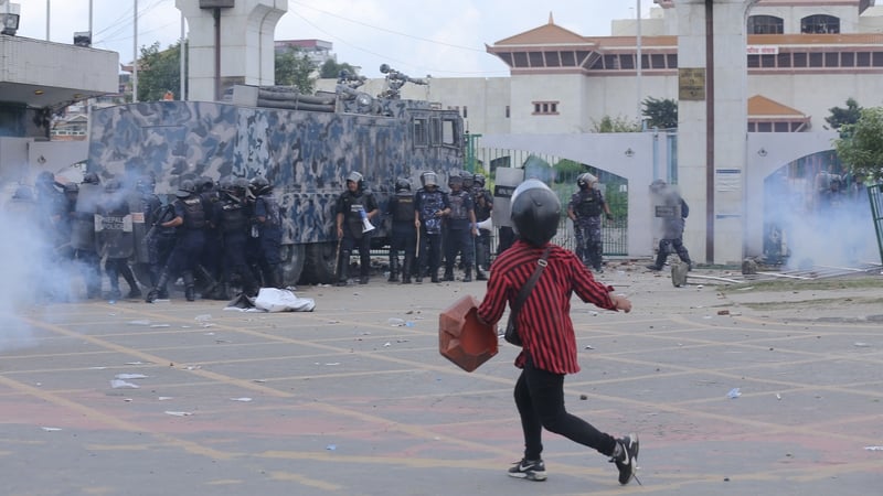 A Nepali student protester stands in front of police during a protest near the Federal Parliament building in Kathmandu