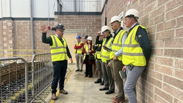 A group of people wearing high vis jackets and hard hats visit a factory in the midlands