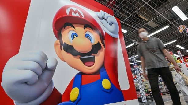 A shopper walks past a Super Mario display on the wall of an electronics store in the popular shopping area of Akihabara in central Tokyo