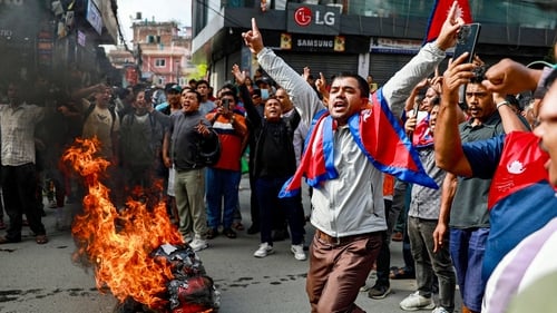 People displaying Nepal's national flag burn tyres during protests triggered by a social media ban