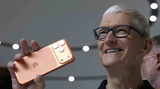 A man holds up an orange Apple iPhone