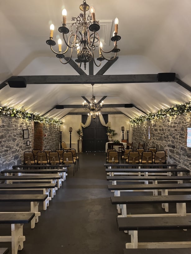 A ceremony room with beams on the ceiling and benches