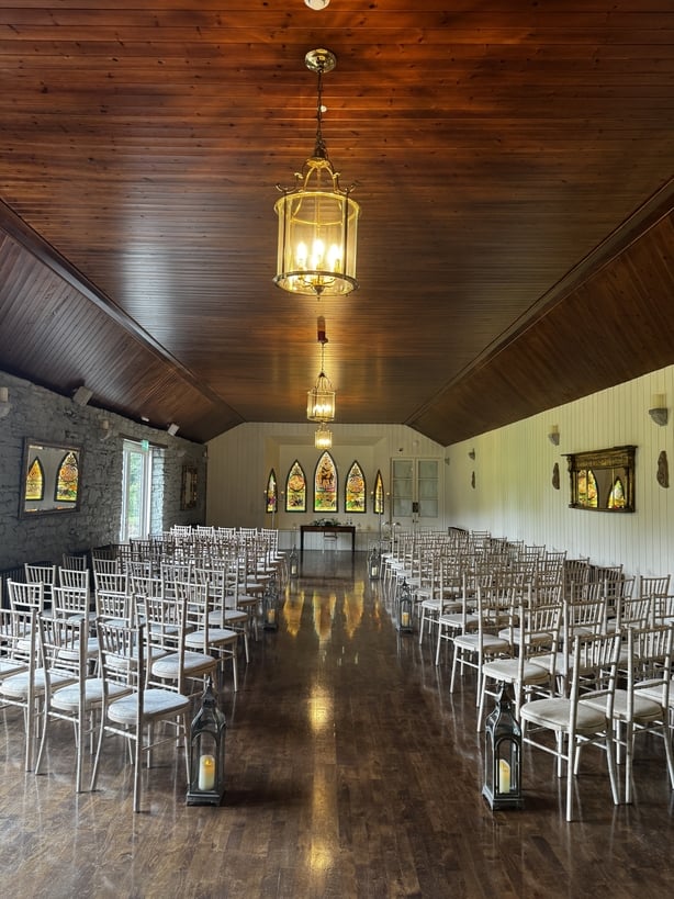A long ceremony room with a wooden ceiling and stained glass windows