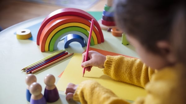 Preschool child drawing on a piece of yellow paper