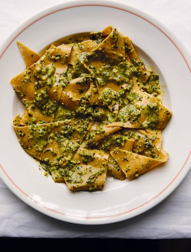 A plate of pasta with green pesto sauce