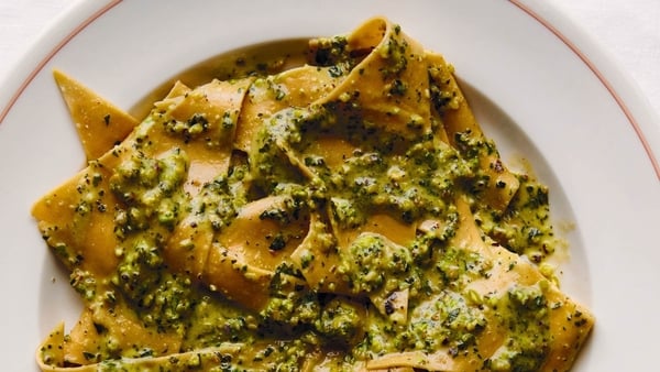 A plate of pasta with green pesto sauce