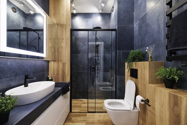 Modern, dark luxury bathroom with indigo and wood like tiles. Black rain shower head. Lacquered white drawers. Modern mirror with built-in led illumination.Canon R5.