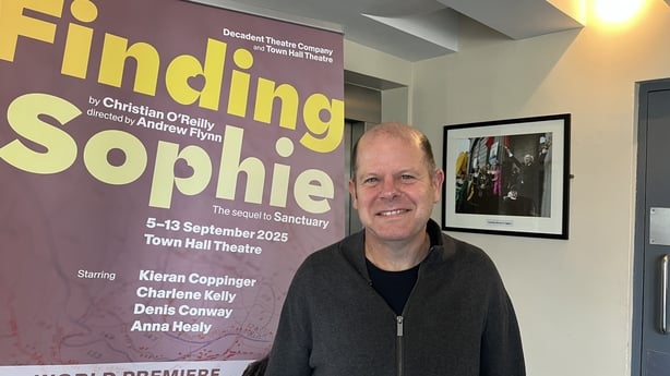 Writer Christian O'Reilly stands next to a poster for his play 'Finding Sophie'