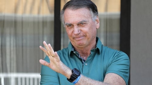 Former Brazilian President Jair Bolsonaro waves from his residence in Brasilia yesterday