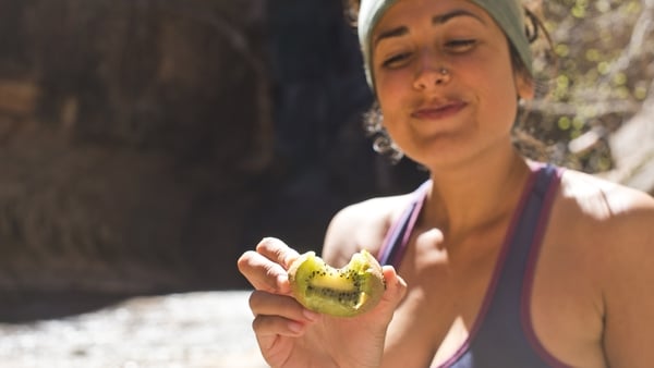 healthy woman hiking and eating kiwi