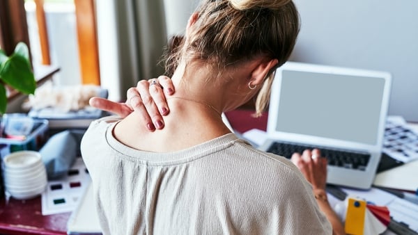 Rearview shot of a designer experiencing discomfort in her shoulders while sitting at her desk