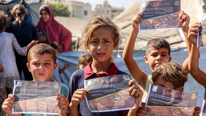 Children hold evacuation orders dropped by the Israeli military on Gaza City