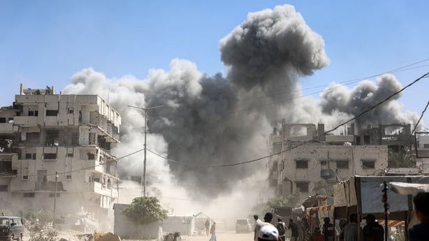 Palestinians watch as the Mhanna tower collapses amid heavy smoke in Gaza City