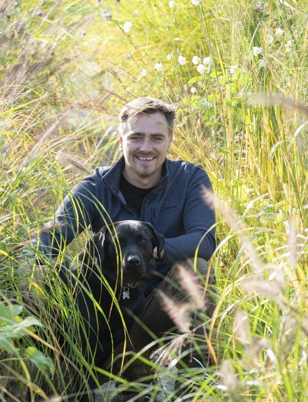 A man posing for a photo in a grassy field