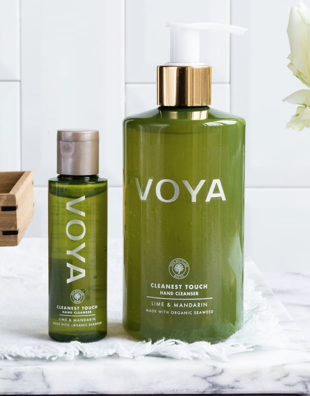 An image of two skin cream products in green containers on a table