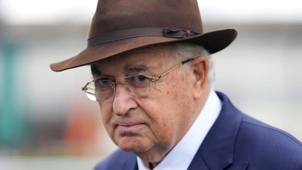 John Magnier looks to camera wearing a hat and a suit