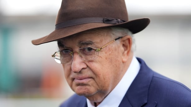 John Magnier looks to camera wearing a hat and a suit