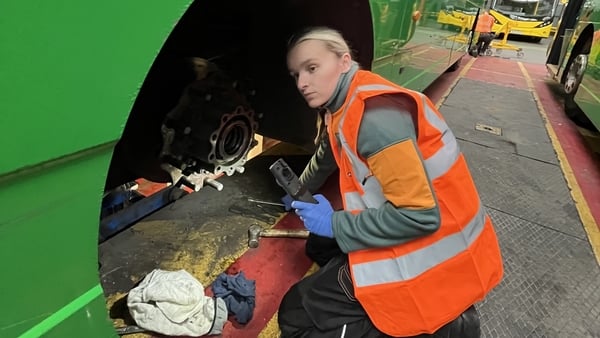 Hollie McCabe working on a bus wheel in an orange hi-viz