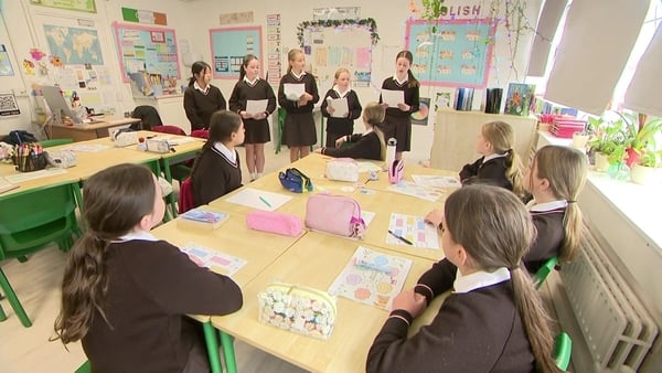 Five girls stand in front of their class giving a presentation.