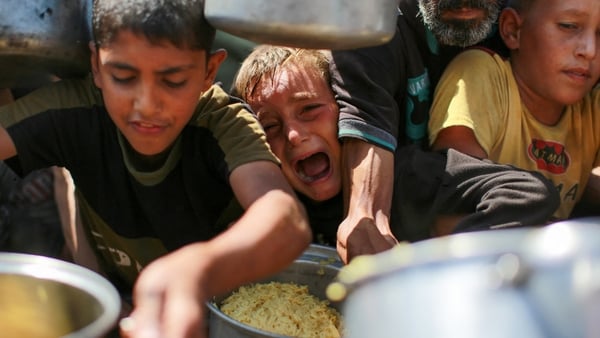 Children try to get rice from a charity kitchen providing food for free in the west of Gaza City