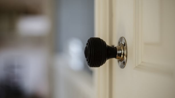 Close up of black doorknob handle on white door with room out of focus in the distance