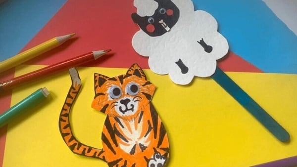 Kids artwork on yello, red and blue coloured paper with a cat and sheep stick puppets.