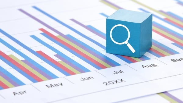 Light blue block with magnifying glass icon on a business chart sheet