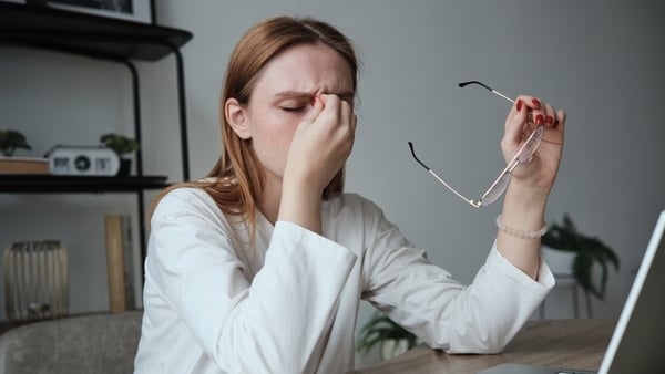 Tired exhausted young woman office worker sitting at table with laptop rubbing nose