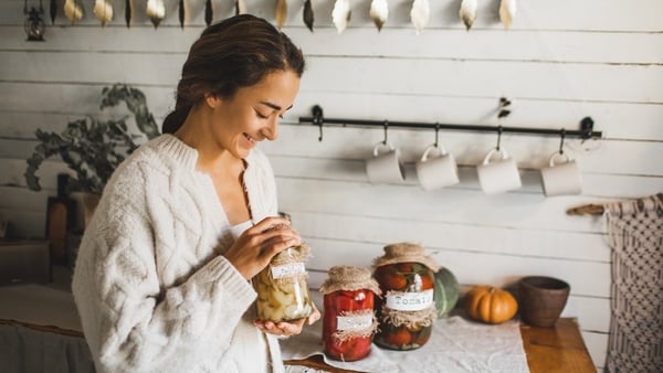 Homemade fermented vegetables canned in jars. Making fermented pickled tomatoes. Canning process, fresh vegetables, jars with preserved vegetarian food on wood rustic table. Healthy eco food and zero waste food concept. Kitchen pantry.