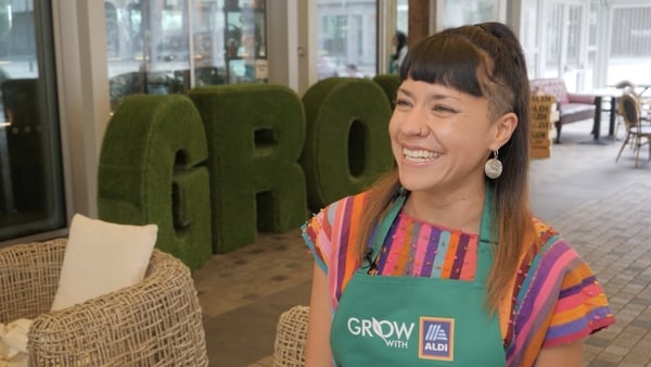A woman in an Aldi green apron smiling by Aldi