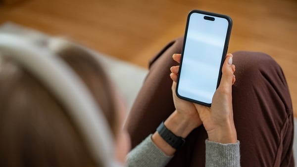 A person is holding a cell phone with a blank screen mock up. The phone has a white screen.
