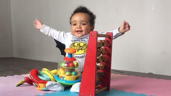 Daniel Aruebuose smiling beside a toy, with his arms outstretched