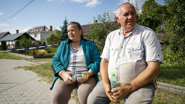 GETTY Alicja (L) sits next to her husband Tomasz Wesolowscy as police and army inspect damage to their house destroyed