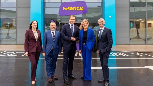 A group of men and women outside a building with the Merck logo