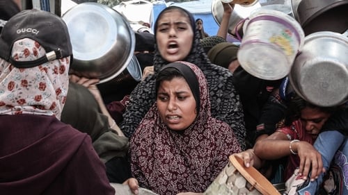 Palestinians queue for food aid at the Nuseirat Refugee Camp
