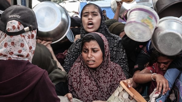 Palestinians, carrying pots and pans, line up for hot meals in Nuseirat Camp in Gaza City